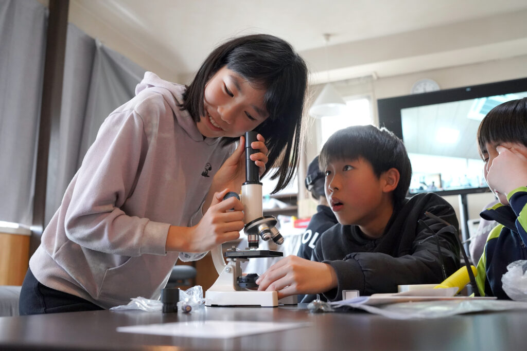 子どもが顕微鏡を覗き込んでいる写真